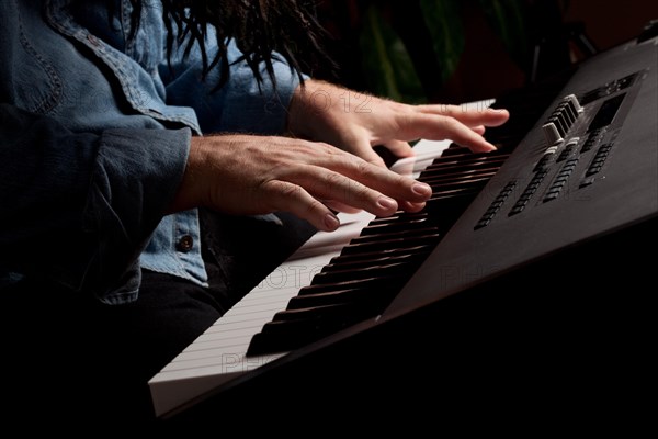 Male pianist performs on the piano keyboard with dramatic lighting