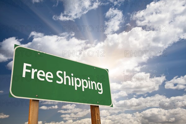 Free shipping green road sign over dramatic sky