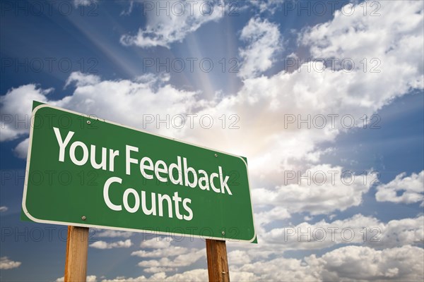 Your feedback counts green road sign with dramatic clouds and sky