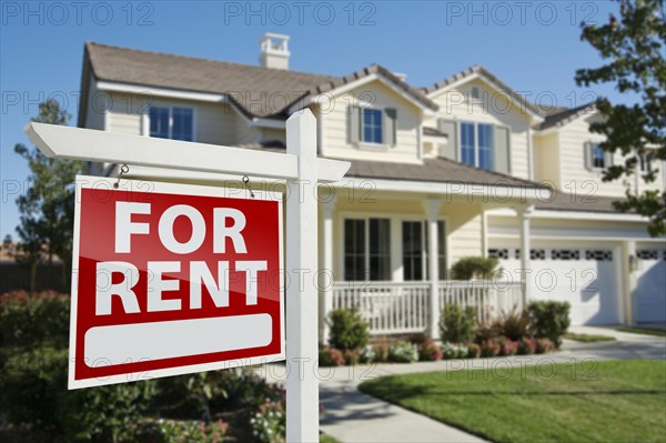 Right facing red for rent real estate sign in front of beautiful house