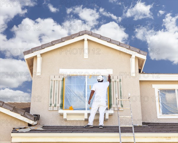 Busy house painter painting the trim and shutters of A home