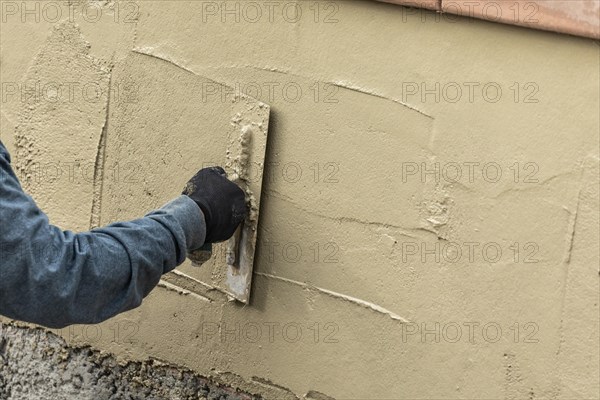 Tile worker applying cement with trowel at pool construction site