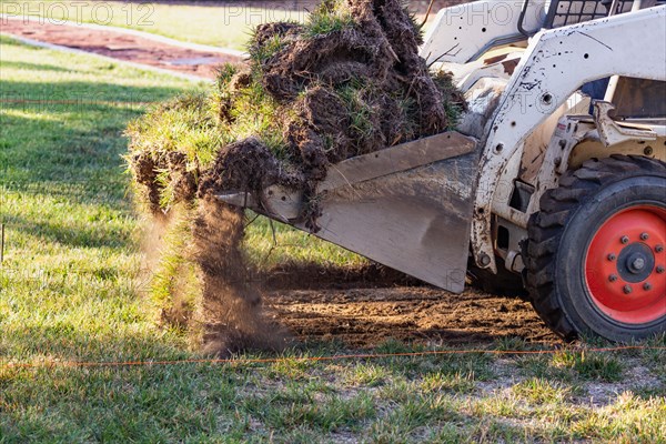 Small bulldozer removing grass from yard preparing for pool installation