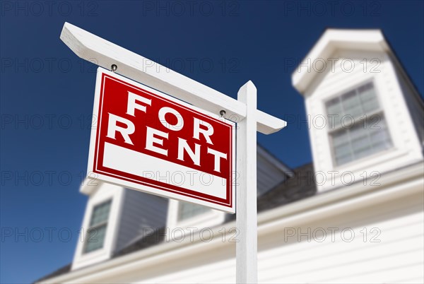 Left facing for rent real estate sign in front of house and deep blue sky