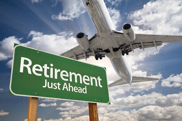 Retirement green road sign and airplane above with dramatic blue sky and clouds