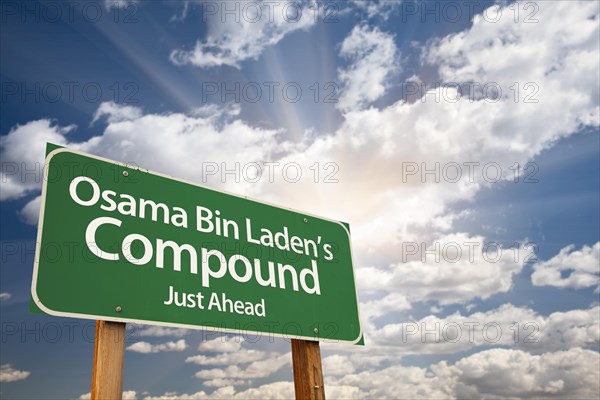 Osama bin laden's compound green road sign on dramatic blue sky with clouds