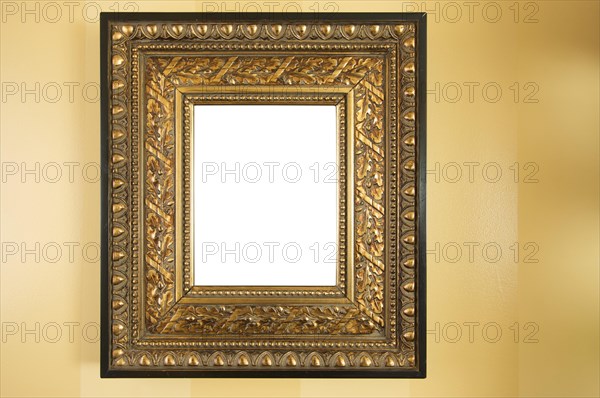 Ornate blank picture frame on yellow wall