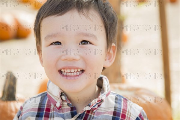 Cute mixed-race young boy having fun at the pumpkin patch