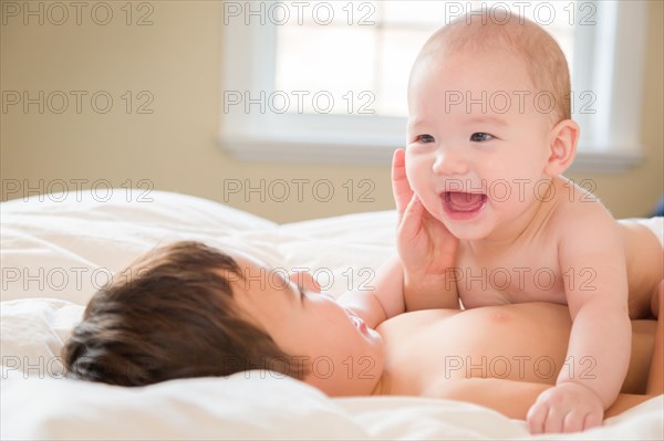 Young mixed-race chinese and caucasian baby brothers having fun on their blanket