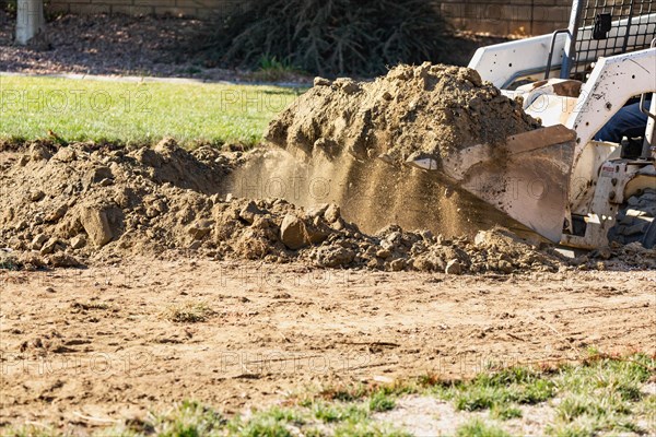 Small bulldozer digging in yard for pool installation