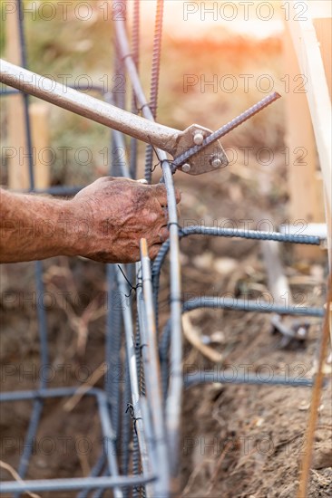 Worker using tools to bend steel rebar at construction site