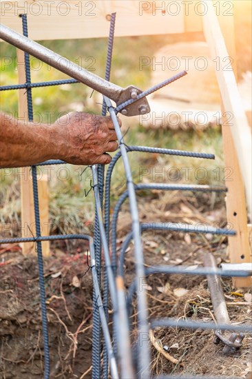 Worker using tools to bend steel rebar at construction site