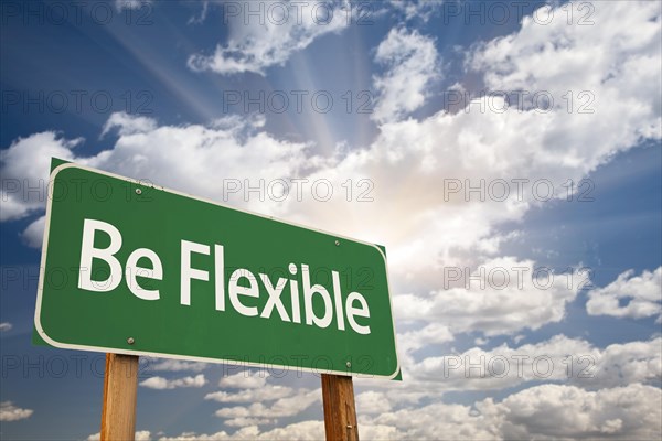 Be flexible green road sign with dramatic clouds and sky