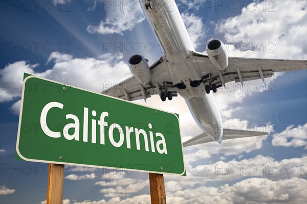 California green road sign and airplane above with dramatic blue sky and clouds
