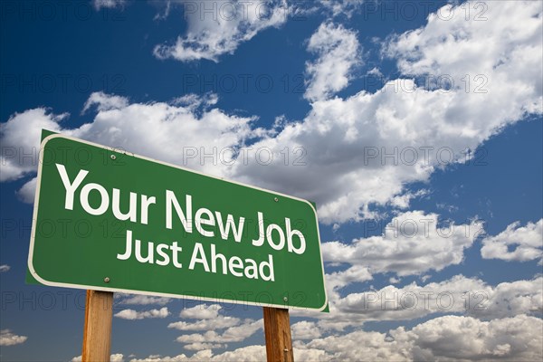 Your new job green road sign over dramatic clouds and sky