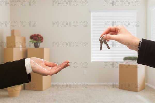 Woman handing over house keys in room with packed moving boxes