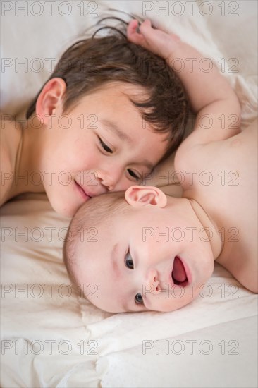 Young mixed-race chinese and caucasian baby brothers having fun on their blanket