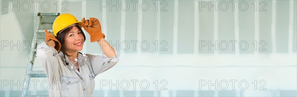 Hispanic female contractor wearing hard hat against drywall banner background with ladder