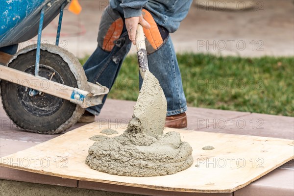 Construction worker placing wet cement on board at pool construction site