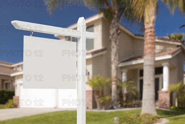 Blank real estate sign in front of beautiful new house