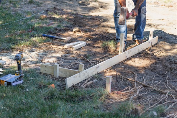 Worker installing stakes and lumber guides at construction site