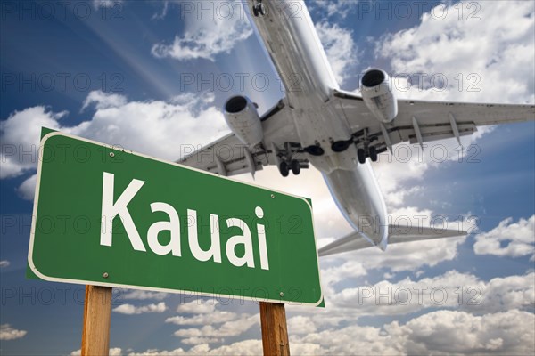 Kauai green road sign and airplane above with dramatic blue sky and clouds