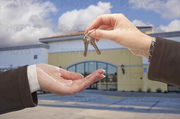 Real estate agent handing over the keys in front of vacant business office