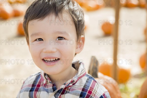 Cute mixed-race young boy having fun at the pumpkin patch