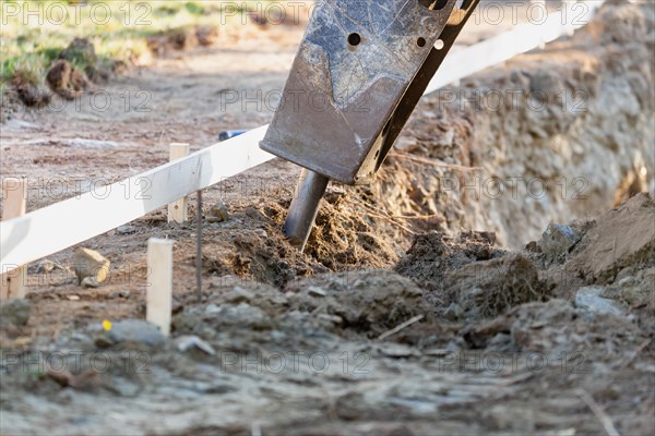 Small bulldozer using A breaker attachment to dig hole