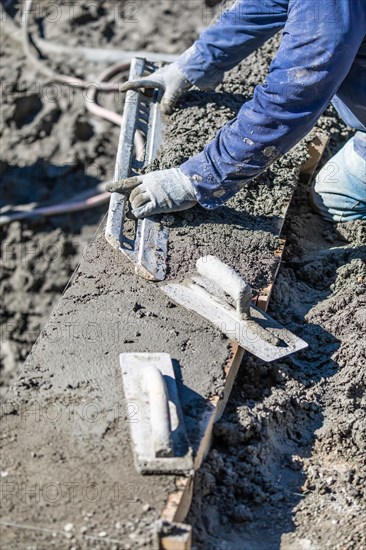 Pool construction worker working with A smoother rod on wet concrete