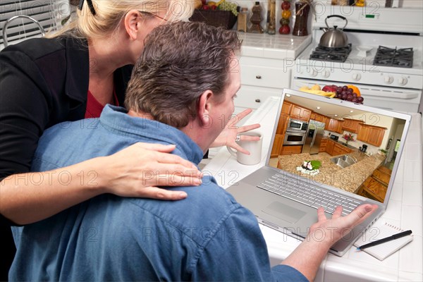 Couple in kitchen using laptop to research home improvement ideas. screen can be easily used for your own message or picture. picture on screen is my copyright as well