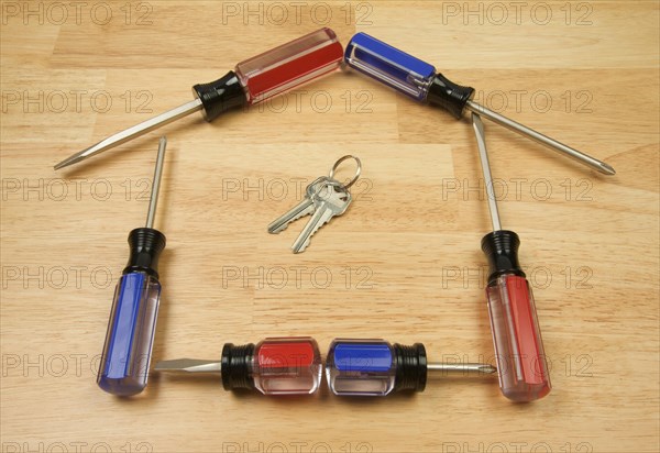 House shaped by screwdrivers and keys on a wood background