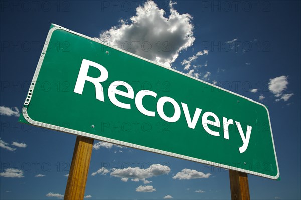 Recovery green road sign with dramatic clouds and sky