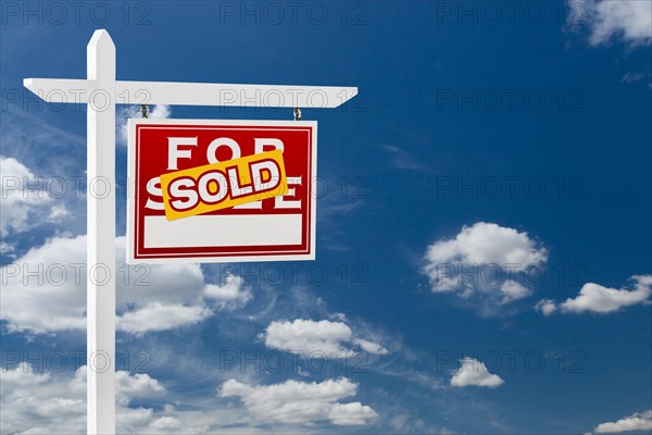 Right facing sold for sale real estate sign over blue sky and clouds with room for your text