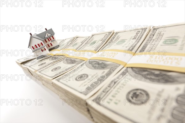 Small house on row of hundred dollar bill stacks isolated on a white background