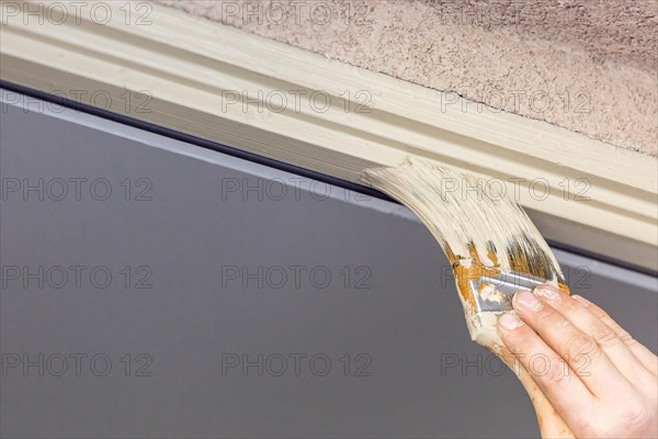 Professional painter cutting in with A brush to paint house door frame