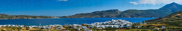 View of Plaka village with traditional Greek church and white painted houses and ocean coast. Milos island