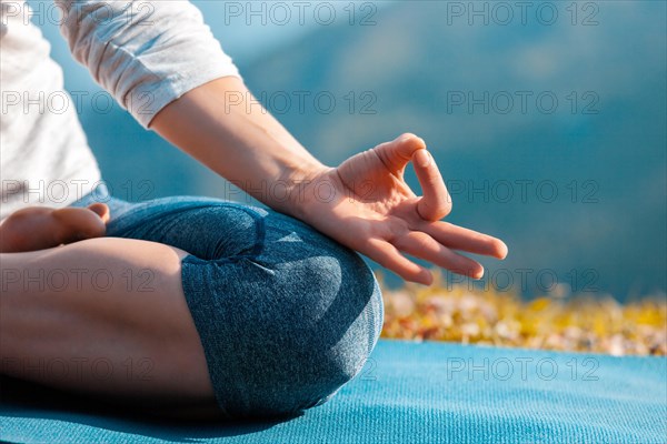 Close up of woman in Padmasana yoga lotus pose with chin mudra outdoors with copyspace. Teal orange color grading