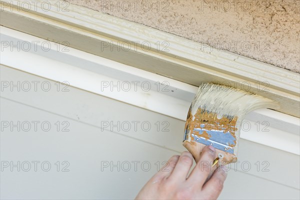 Professional painter cutting in with A brush to paint garage door frame