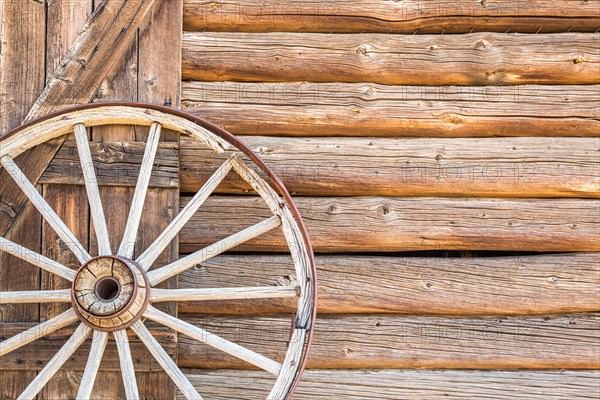 Abstract of vintage antique log cabin wall and wagon wheel