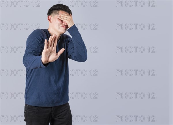 Scared confused man closing eyes with palm of hand