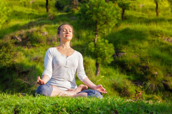 Young sporty fit woman doing yoga outdoors