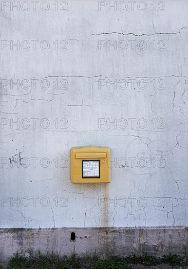 Yellow Deutsche Post letterbox on white wall