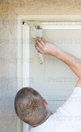 Professional painter cutting in with A brush to paint garage door frame