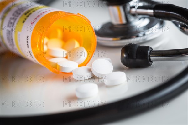 Non-Proprietary medicine prescription bottles and spilled pills abstract with stethoscope