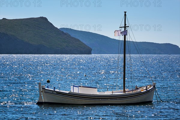Traditional greek fishing boat in the Aegean sea with greek flag