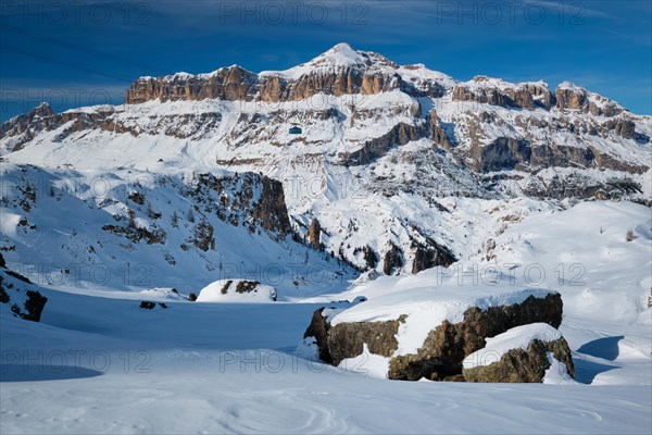 View of a ski resort piste with people skiing in Dolomites in Italy with cable car ski lift Ski area Arabba Arabba