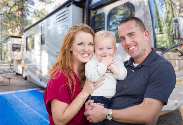 Happy young military family in front of their beautiful RV at the campground