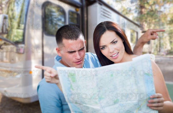 Young lost and confused military couple looking at map in front of RV