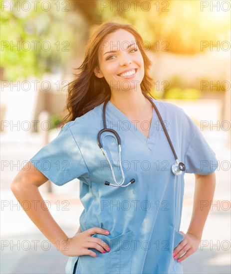 Portrait of young adult female doctor or nurse wearing scrubs and stethoscope outside